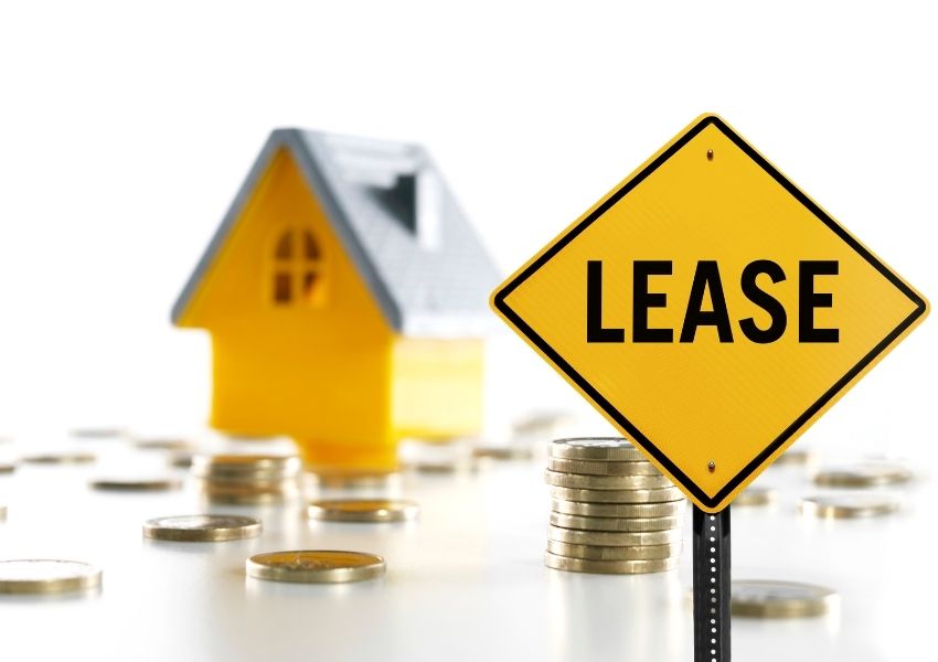 a yellow sign that says lease with a house figurine and coins in the background